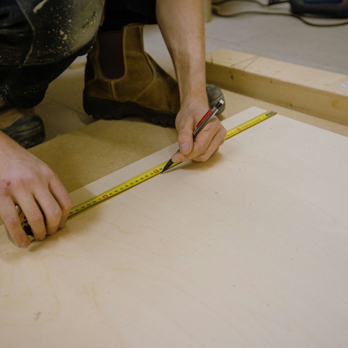 Carpenter measuring and marking a wood panel